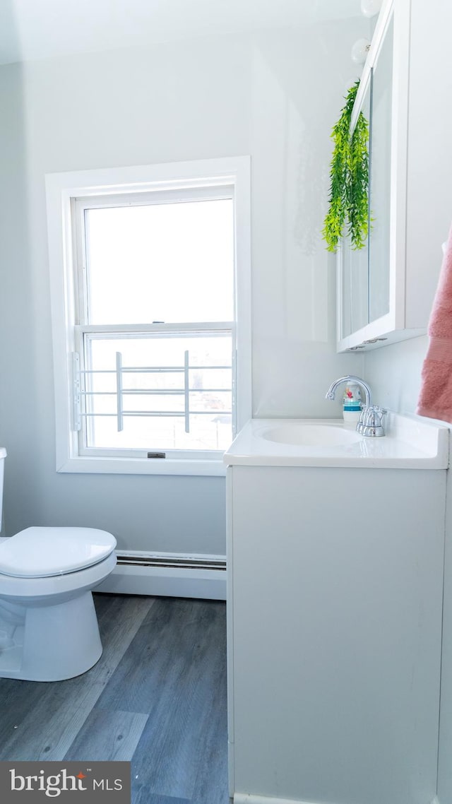 bathroom featuring baseboard heating, toilet, vanity, and hardwood / wood-style flooring