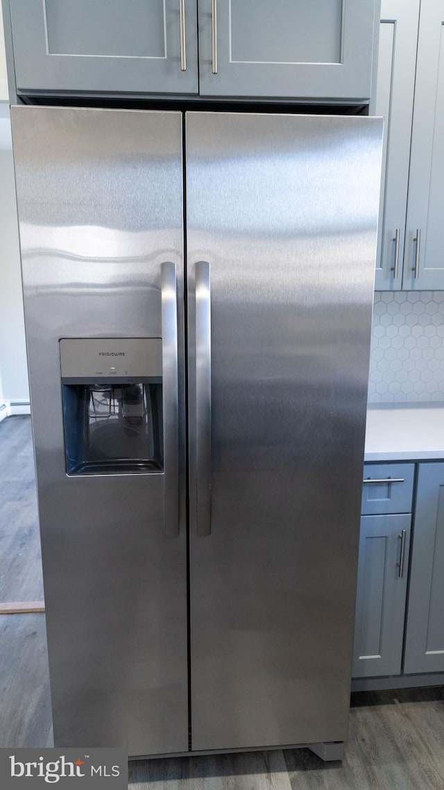 room details featuring stainless steel refrigerator with ice dispenser, tasteful backsplash, gray cabinetry, and dark wood-type flooring