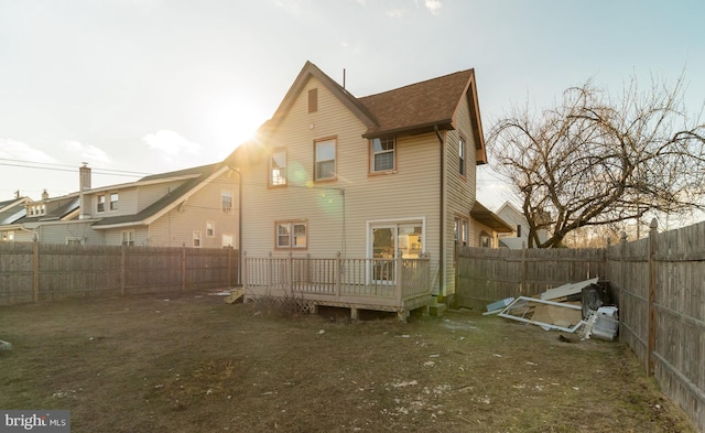 back of property with a deck and a yard