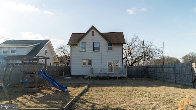 back of property with a yard, a playground, and a wooden deck