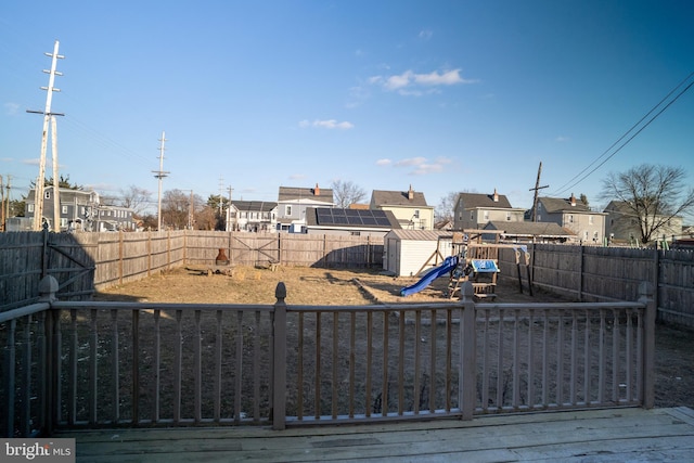 view of yard featuring a deck, a playground, and a storage unit