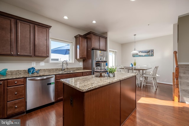 kitchen with pendant lighting, dark hardwood / wood-style floors, a center island, appliances with stainless steel finishes, and sink