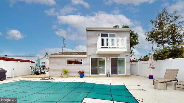 back of house featuring a balcony, a covered pool, and a patio