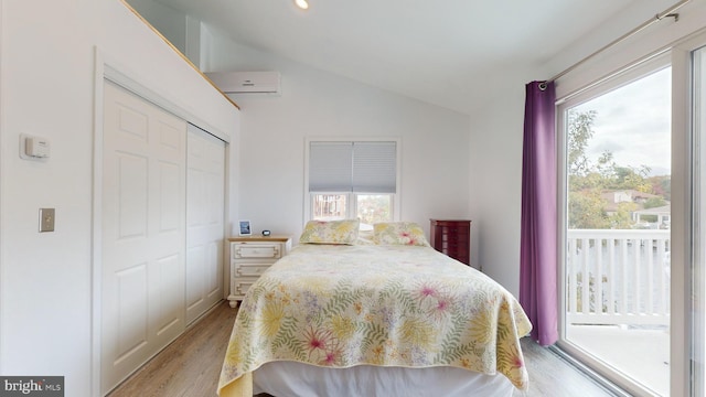 bedroom with vaulted ceiling, a closet, light hardwood / wood-style floors, and multiple windows