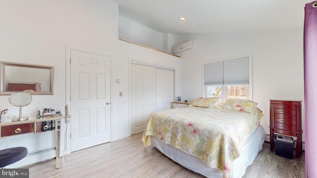 bedroom featuring vaulted ceiling, an AC wall unit, a closet, and light hardwood / wood-style floors