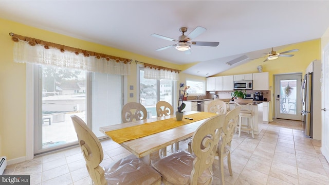 tiled dining room featuring ceiling fan, vaulted ceiling, a baseboard radiator, and a wealth of natural light