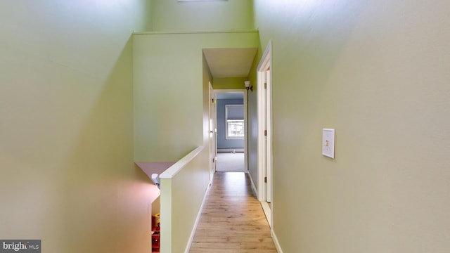 corridor with baseboard heating and light hardwood / wood-style flooring