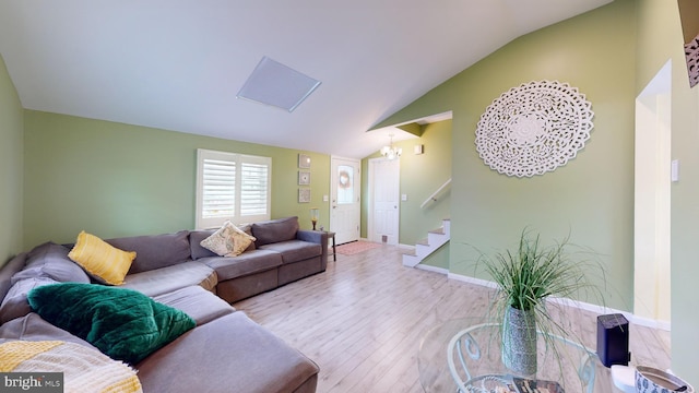 living room with lofted ceiling, an inviting chandelier, and light hardwood / wood-style floors