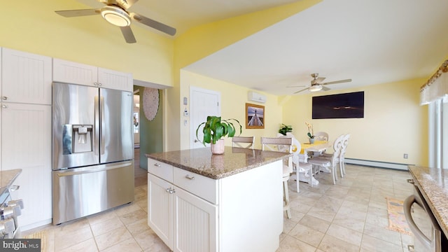 kitchen featuring stainless steel appliances, white cabinets, dark stone counters, a kitchen island, and baseboard heating