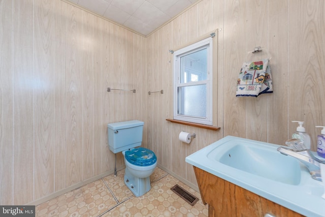 bathroom featuring sink, wood walls, and toilet