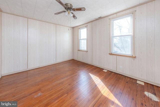 empty room with ceiling fan, a healthy amount of sunlight, and wood-type flooring