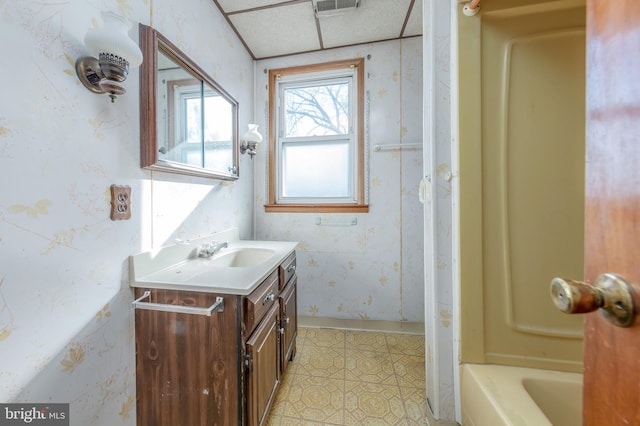 bathroom featuring a bath, a paneled ceiling, and vanity