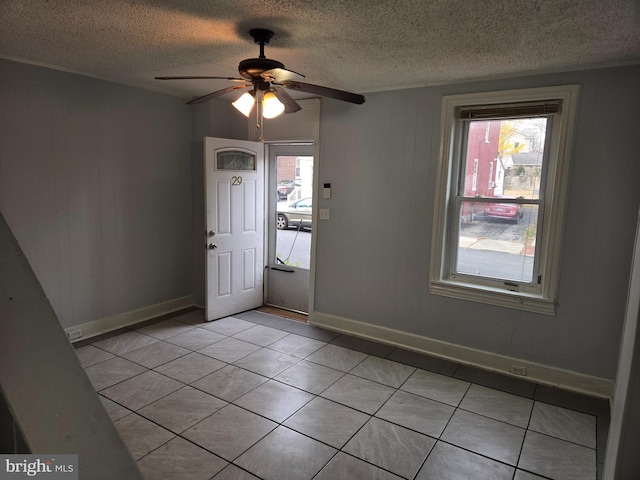 tiled foyer entrance with a textured ceiling and ceiling fan