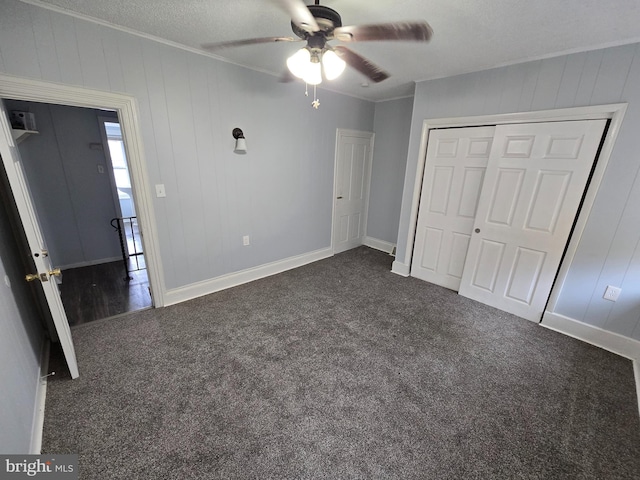 unfurnished bedroom with ceiling fan, a closet, a textured ceiling, and dark carpet