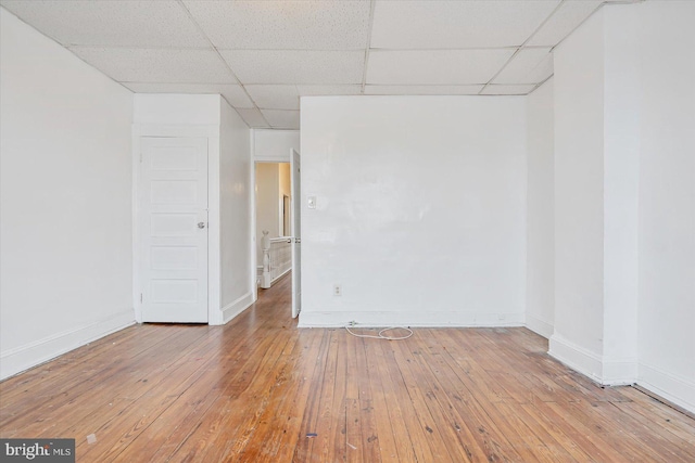 empty room featuring a paneled ceiling and hardwood / wood-style flooring