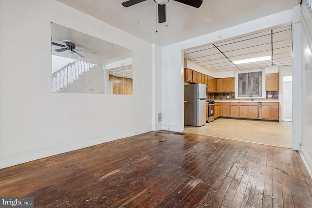 unfurnished living room featuring ceiling fan, light hardwood / wood-style flooring, and sink