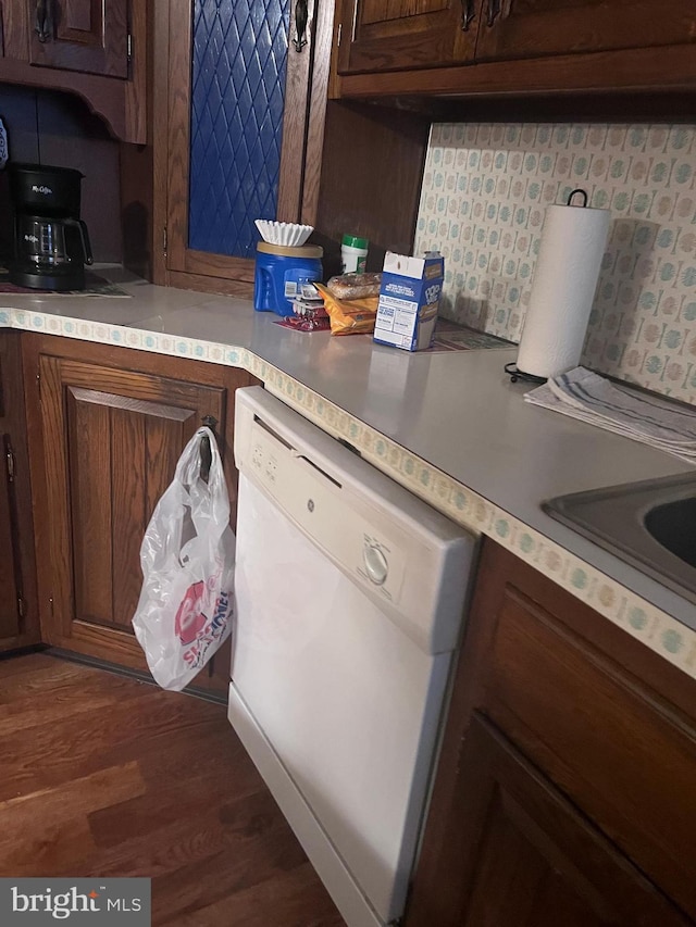 kitchen with dark wood-type flooring, backsplash, dark brown cabinetry, and dishwasher