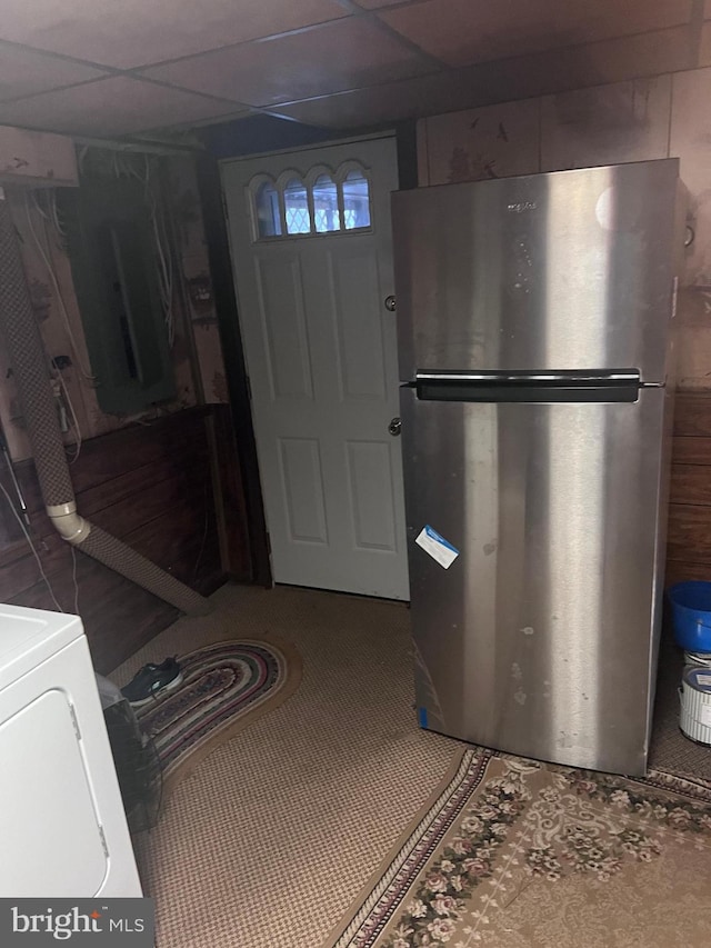 interior space featuring a paneled ceiling, washer / clothes dryer, and stainless steel refrigerator