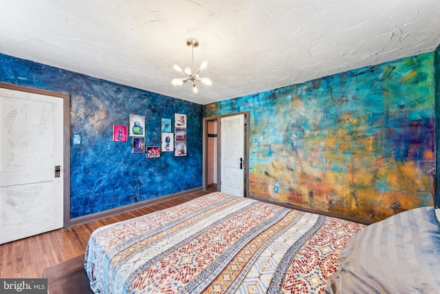 bedroom with hardwood / wood-style floors and an inviting chandelier