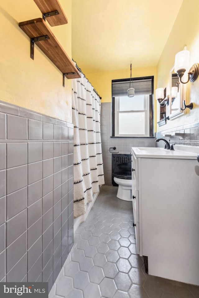 bathroom with vanity, toilet, tile walls, and tile patterned floors