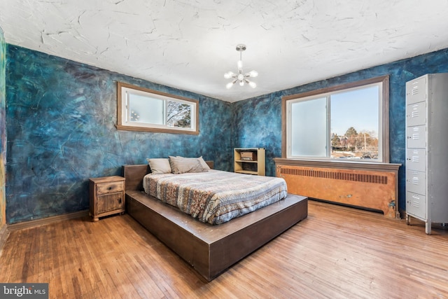 bedroom with a notable chandelier, radiator heating unit, and wood-type flooring