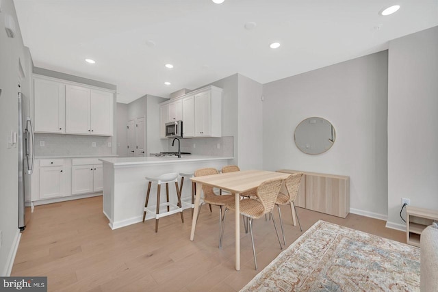 kitchen featuring white cabinetry, tasteful backsplash, stainless steel appliances, and a breakfast bar area