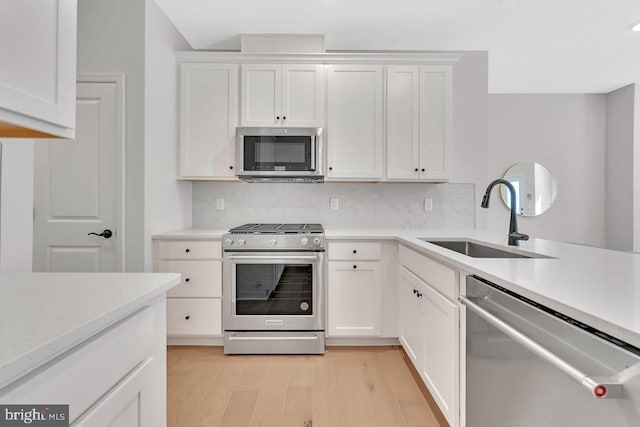 kitchen featuring sink, white cabinetry, tasteful backsplash, appliances with stainless steel finishes, and light hardwood / wood-style floors