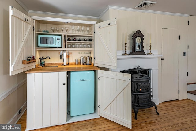 bar with sink, ornamental molding, and light wood-type flooring