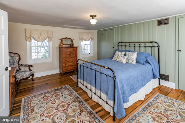 bedroom with multiple windows and dark wood-type flooring