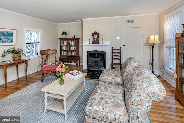 living room featuring hardwood / wood-style floors, crown molding, and a wood stove