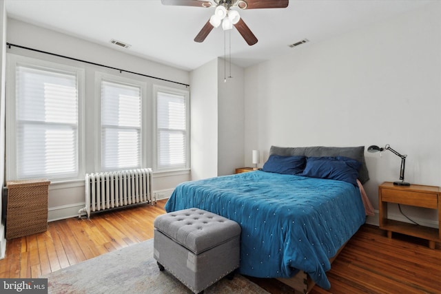 bedroom with ceiling fan, dark hardwood / wood-style floors, and radiator