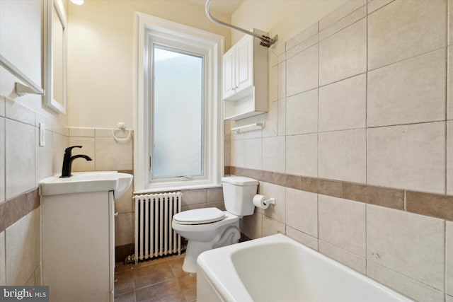 bathroom featuring tile walls, a washtub, radiator heating unit, and vanity