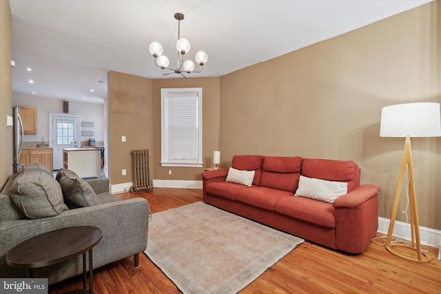 living room with radiator, a chandelier, and light hardwood / wood-style flooring