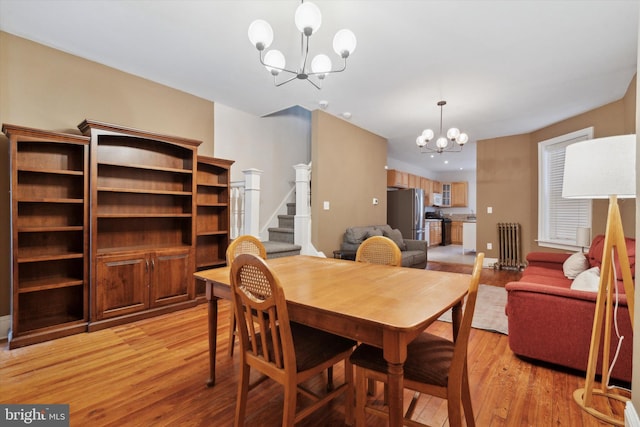 dining space with light hardwood / wood-style floors, radiator heating unit, and a chandelier