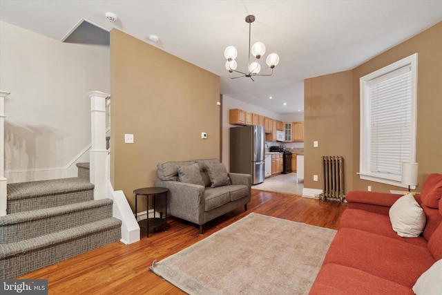 living room featuring light hardwood / wood-style flooring, an inviting chandelier, and radiator heating unit