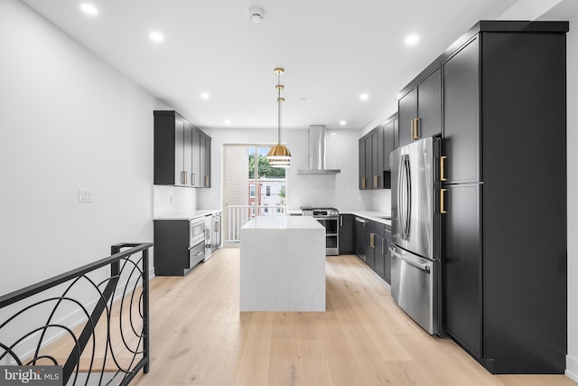 kitchen with pendant lighting, stainless steel appliances, wall chimney range hood, a kitchen island, and backsplash