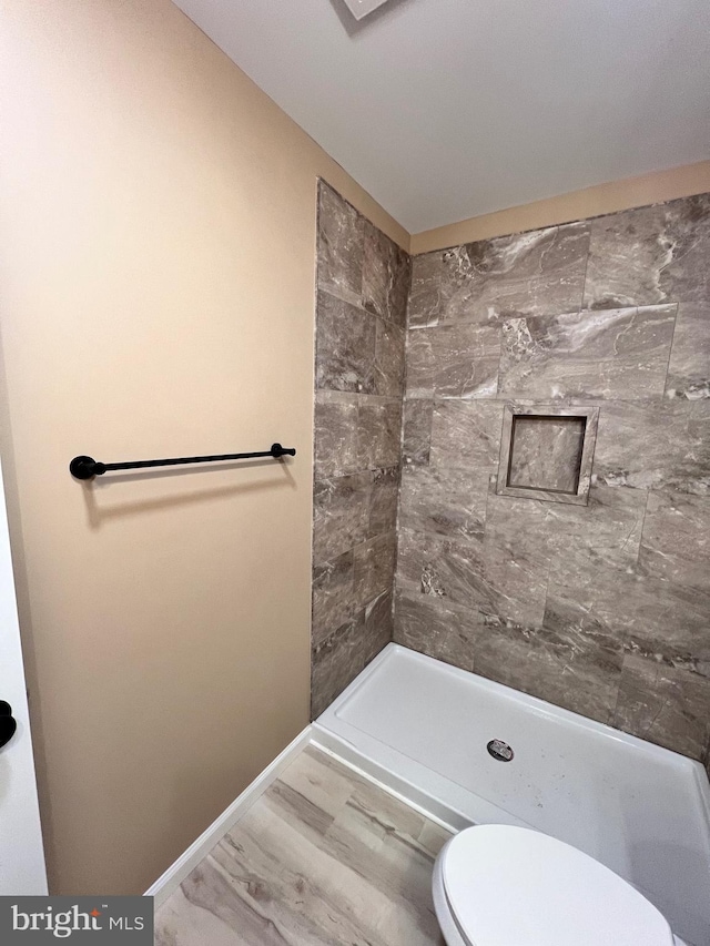 full bath featuring toilet, baseboards, and a shower stall