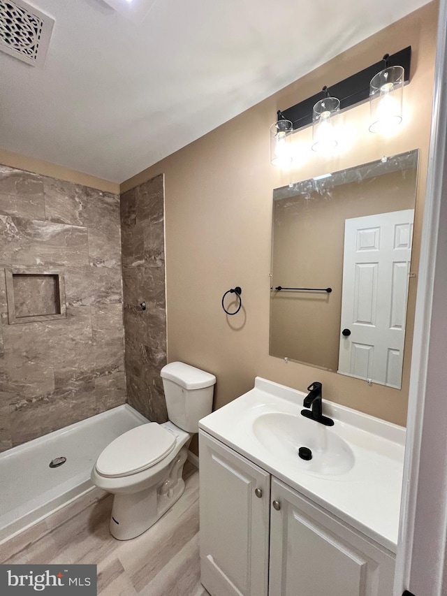 bathroom with vanity, a stall shower, toilet, visible vents, and wood finished floors
