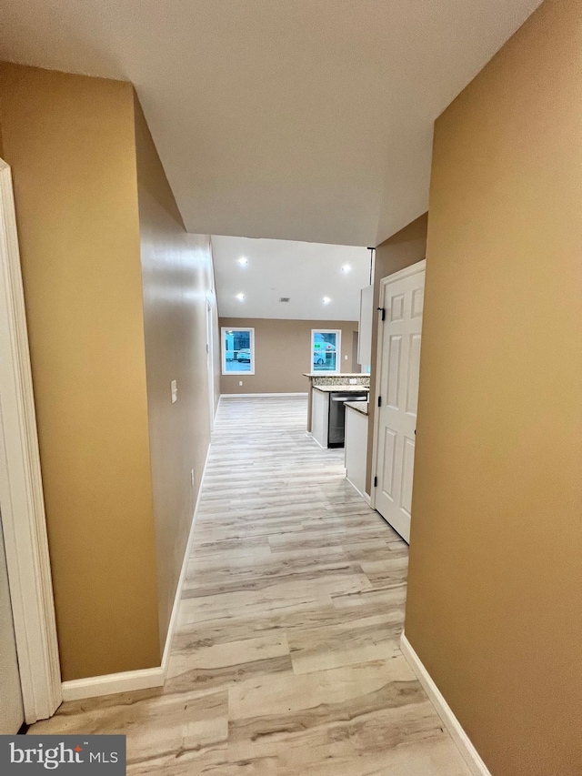 hallway with baseboards, recessed lighting, and light wood-style floors