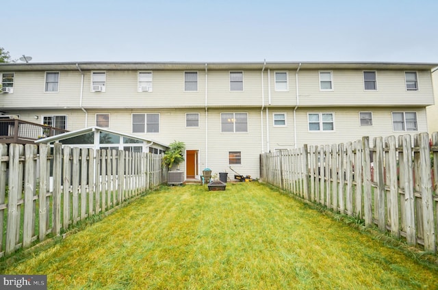 back of property featuring a lawn and central AC