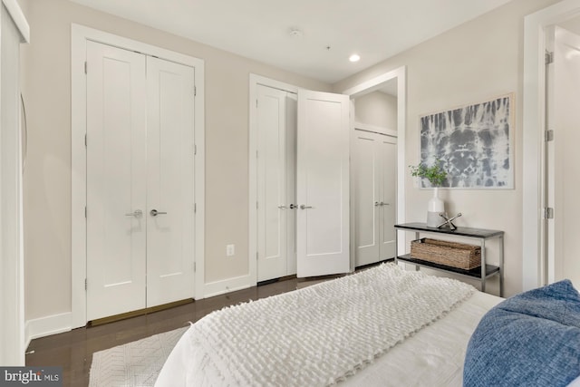 bedroom with two closets and dark wood-type flooring