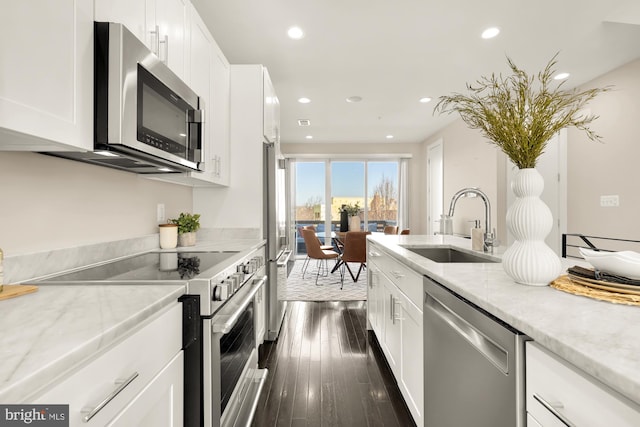 kitchen with light stone countertops, appliances with stainless steel finishes, sink, and white cabinets