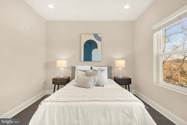 bedroom with multiple windows and dark hardwood / wood-style floors