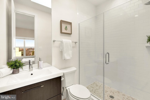 bathroom featuring vanity, a shower with shower door, and toilet