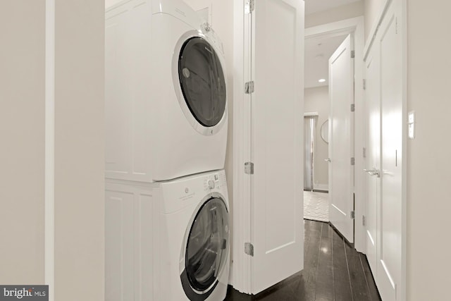 clothes washing area featuring stacked washer / dryer and dark hardwood / wood-style floors