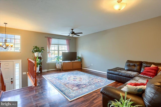 living room with ceiling fan with notable chandelier and dark wood-type flooring