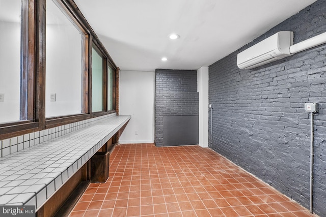 interior space with brick wall, a wall mounted AC, and tile patterned floors