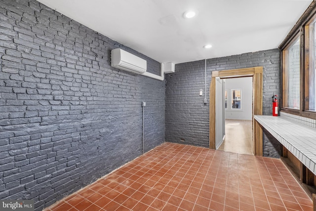 interior space featuring tile patterned floors, an AC wall unit, and brick wall