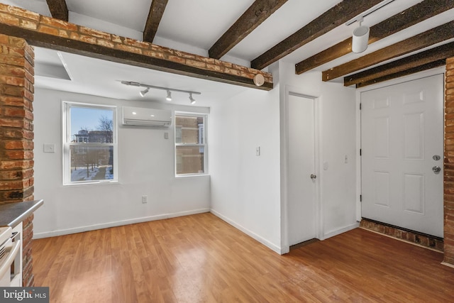 entrance foyer with beam ceiling, a wall mounted AC, and light hardwood / wood-style floors