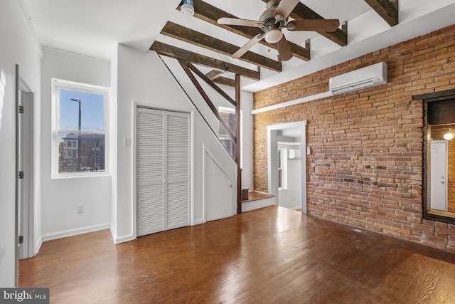 interior space featuring a wall mounted air conditioner, lofted ceiling with beams, hardwood / wood-style flooring, ceiling fan, and brick wall